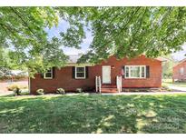 Charming red brick home with manicured lawn and landscaping, exuding curb appeal and welcoming ambiance at 704 Kingman Dr, Charlotte, NC 28217