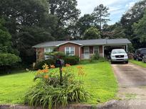 Charming brick home with a well-manicured lawn, colorful flowers, and a convenient carport at 910 Mcgowan Rd, Shelby, NC 28150