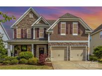 Charming two-story home featuring a stone and shingle facade, well-manicured landscaping, and a two-car garage at 11014 Aspen Ridge Nw Ln, Concord, NC 28027
