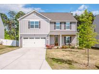 Charming two-story home with gray siding, a two-car garage, well-manicured lawn and freshly landscaped flowerbeds at 112 Tanner Loop, Troutman, NC 28166