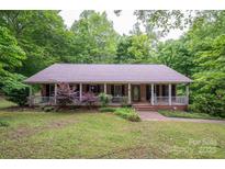 Charming single-story home with a covered porch and lush greenery creating a private, serene setting at 480 S Ingleside Farm Rd, Iron Station, NC 28080