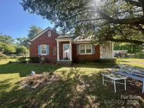 Charming brick home with a covered porch, blue shutters, and beautiful landscaping at 6585 White St, Kershaw, SC 29067