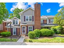 Charming townhouse with a brick chimney, gray siding, and well-maintained landscaping at 9214 N Vicksburg Park Ct, Charlotte, NC 28210