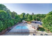 Aerial view of a community pool with lots of trees and parking at 1000 E Woodlawn Rd # 402, Charlotte, NC 28209