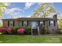 Charming brick home featuring a well-maintained lawn and flowering shrubs, creating a welcoming curb appeal at 1009 N Main St, Mount Holly, NC 28120