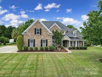 Charming two-story brick home with manicured lawn, lush landscaping, and classic black shutters offers elegant curb appeal at 2218 Legacy Oak Dr, Waxhaw, NC 28173