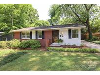 Charming red brick and white home with black shutters and a well-manicured lawn at 4361 Applegate Rd, Charlotte, NC 28209