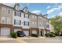 View of townhome exterior with brick accents, multiple floors, and garages at 6912 Park Place Dr, Charlotte, NC 28262