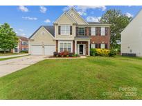 Traditional two-story home featuring a manicured lawn, brick accents, and an attached two-car garage at 8709 Barrelli Ct, Charlotte, NC 28277