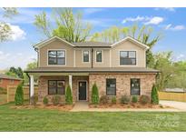 Two-story home featuring a brick facade, covered porch, neutral siding, black framed windows, and landscaped front yard at 8717 Lawyers Rd, Charlotte, NC 28227