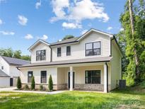 Charming two-story home with neutral siding, black trim, front porch, and well-manicured lawn at 8717 Lawyers Rd, Charlotte, NC 28227