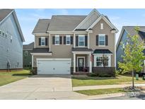 Charming two-story home features a two-car garage, manicured lawn, and an inviting front porch at 1005 Cheviot Ct, Waxhaw, NC 28173