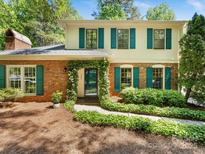 Charming two-story brick home featuring green shutters, a lush ivy-covered entrance, and manicured landscaping at 1325 Rock Point Rd, Charlotte, NC 28270