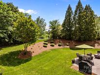 Green backyard featuring a table with an umbrella, landscaping, and stairs to the upper yard at 1900 Birchbrook Ct, Harrisburg, NC 28075