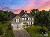 Stunning two-story home with a well-manicured lawn and attached two car garage, set against a beautiful sunset sky at 1900 Birchbrook Ct, Harrisburg, NC 28075