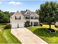 Two-story home featuring a manicured lawn, a long driveway leading to a two-car garage, and mature landscaping at 1900 Birchbrook Ct, Harrisburg, NC 28075