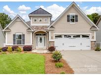 Charming home featuring stone accents, a two-car garage, manicured lawn and a covered front porch at 581 Harrison Nw Dr, Concord, NC 28027