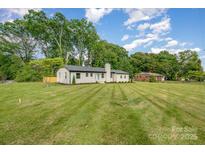 Charming single-story home featuring freshly cut grass and a painted brick facade and a bright teal front door at 6301 Vernedale Rd, Charlotte, NC 28212