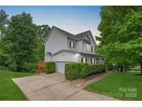 Charming home with white siding, black shutters, a well-manicured lawn, and mature trees at 7049 Sedgebrook W Dr, Stanley, NC 28164