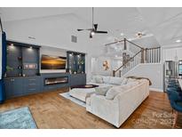 Spacious living room featuring a cozy fireplace, custom built-ins, and a soaring vaulted ceiling at 7730 Burning Ridge Dr, Stanley, NC 28164