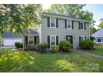 Charming two-story home with a manicured front yard and lush landscaping at 9801 Kent Village Dr, Charlotte, NC 28269