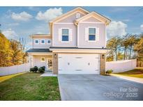 Charming two-story home with a brick-accented two-car garage and well-manicured lawn on a sunny day at 104 Trellis Ln, Troutman, NC 28166