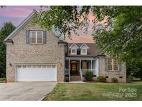 Charming brick home with a well-manicured lawn and a two-car garage, enhanced by a colorful sunset backdrop at 14807 Middlesborough Dr, Matthews, NC 28104