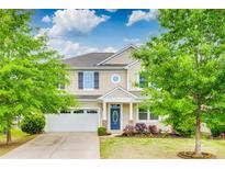 Charming two-story home featuring a well-manicured lawn, blue door, and attached two-car garage at 1507 Arcadia Bluff Dr, York, SC 29745