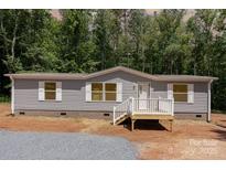 Charming single-story home with gray siding, white trim, and a small front porch nestled among lush green trees at 1785 Doe Ct, Iron Station, NC 28080