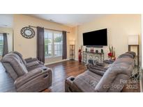 Inviting living room with hardwood floors, recliner seating, and natural light from a large window at 4208 Carl Parmer Dr, Harrisburg, NC 28075