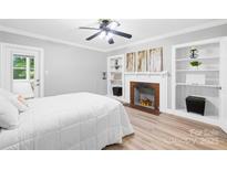 Cozy bedroom features a decorative fireplace, wood floors, and built-in shelving at 6012 Tuckaseegee Rd, Charlotte, NC 28208