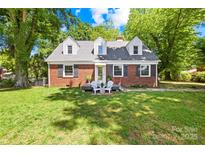 Charming brick home with dormer windows, black shutters, and manicured lawn at 6012 Tuckaseegee Rd, Charlotte, NC 28208