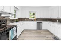 A modern kitchen featuring white cabinets, stainless steel appliances, and a decorative backsplash at 6012 Tuckaseegee Rd, Charlotte, NC 28208