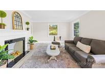 Cozy living room features a fireplace, plush rug, neutral decor, and bright windows at 6012 Tuckaseegee Rd, Charlotte, NC 28208