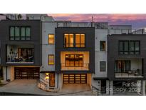 Modern townhouse with a dark garage door, balcony, and a combination of white brick and dark siding, set against a colorful dusk sky at 614 Queens Rd, Charlotte, NC 28207