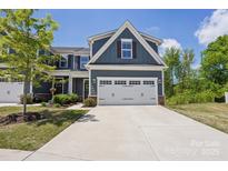 Charming home with a two-car garage, a manicured lawn and blue siding at 6295 Ashton Park Dr, Denver, NC 28037