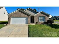 Charming brick home with well-maintained lawn and attached two-car garage, offering curb appeal at 8551 Appledale Dr, Charlotte, NC 28262