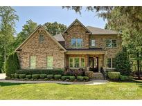 Beautiful, two-story brick and stone home featuring a landscaped front yard, covered porch, and meticulous shrubbery at 1614 Tarrington Way, Indian Trail, NC 28079