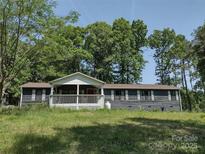 Charming single story home with a cozy covered porch and mature trees surrounding the property at 1820 Trinity Church Rd, Monroe, NC 28112
