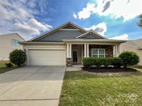 Charming single Gathering home featuring a two-car garage, manicured lawn, and stone accents at 1876 Yellow Daisy Dr, Matthews, NC 28104