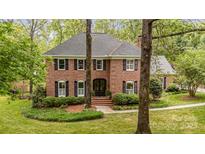 Charming two-story brick home with black shutters, manicured lawn and mature trees at 2600 Oakmeade Dr, Charlotte, NC 28270
