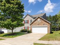 Charming two-story home featuring stone accents, red shutters, a lush lawn, and a driveway leading to a two car garage at 521 Ellingsworth Ln, Charlotte, NC 28214
