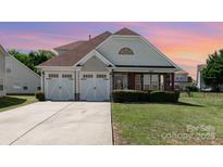 Charming two-story home featuring an attached two-car garage, manicured lawn, and stone-accented porch at 9588 Marquette Nw St, Concord, NC 28027