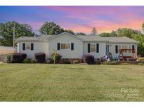 Charming single-story home with a well-manicured lawn and a cozy front porch swing at 106 Rainbow Sw St, Concord, NC 28025