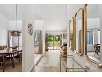 Bright hallway with elegant mirrors that leads to a living area with a fireplace and beautiful view at 11216 Carmel Chace Dr, Charlotte, NC 28226