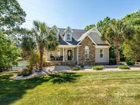 Charming home featuring stone accents, a covered porch, and a beautifully landscaped front yard with mature palm trees at 125 Mariner Pointe Ln, Mooresville, NC 28117