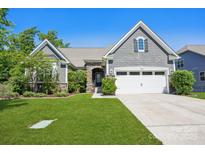Charming home with stone accents, well-manicured lawn, and a two-car garage with a blue sky in the background at 16427 Cozy Cove Rd, Charlotte, NC 28278