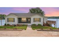 Charming single-story home with a well-manicured lawn, beautiful landscaping, and a lakeside view at 235 River Loop Rd, Belmont, NC 28012