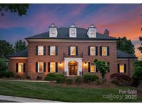 Stately brick home with dormers and manicured lawn at twilight at 3314 Leamington Ln, Charlotte, NC 28226