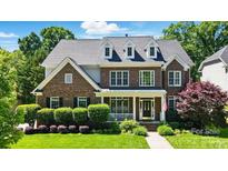 Charming brick two-story home featuring a well-manicured lawn and a welcoming front porch at 7722 Garnkirk Dr, Huntersville, NC 28078